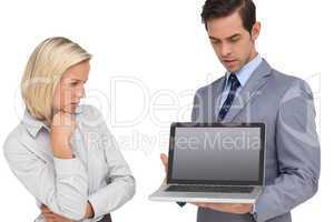 Businesswoman looking at laptop held by her colleague