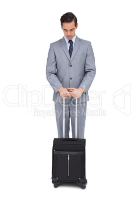 Serious young businessman waiting with his suitcase