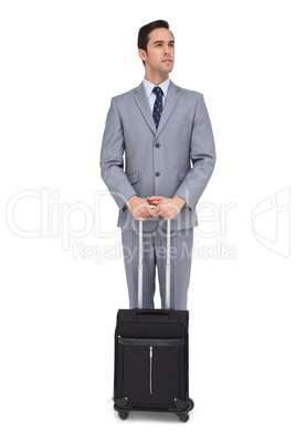 Serious young businessman waiting with his luggage