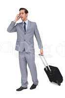 Smiling young businessman with his luggage while phoning