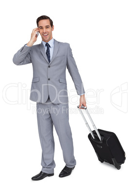 Happy young businessman with his luggage while phoning