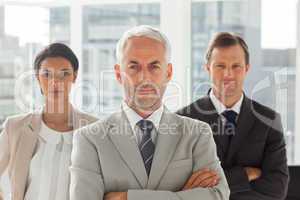 Serious businessman standing with colleagues behind