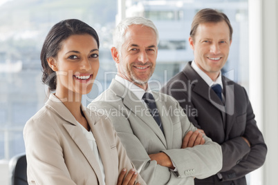 Three business people standing with their arms crossed