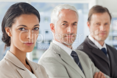 Serious businesswoman smiling with colleagues behind