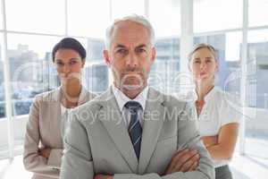 Serious businessman standing in front of colleagues
