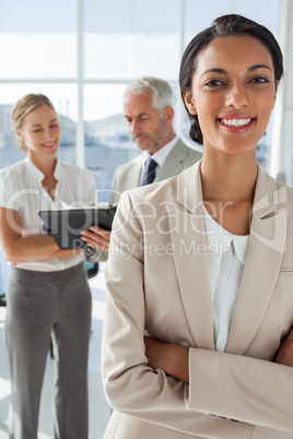 Proud businesswoman in front of colleagues working behind