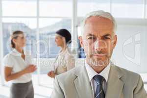Serious businessman standing while colleague are discussing toge