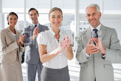 Smiling business people applauding together