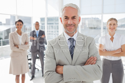 Businessman with arms folded standing in front of colleagues