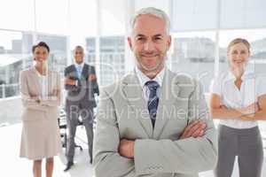 Businessman with arms folded standing in front of colleagues