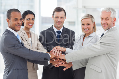 Group of smiling business people piling up their hands together