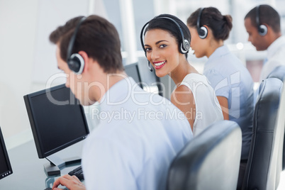 Smiling call centre employee looking over shoulder