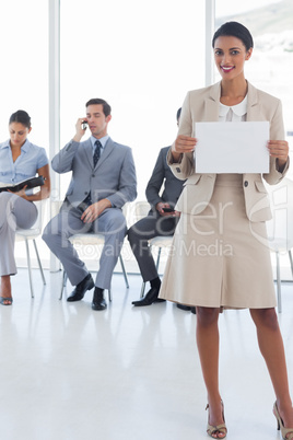 Smiling businesswoman standing and holding a blank notice