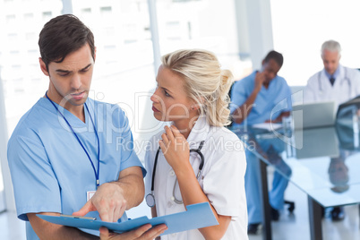 Two doctors talking about a blue file