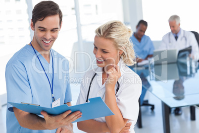Two smiling doctors talking about a blue file