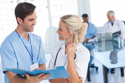 Two young doctors talking about a blue file