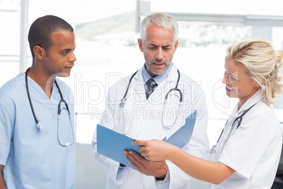 Three serious doctors examining a file