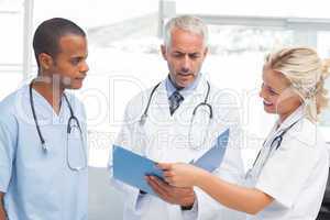 Three serious doctors examining a file