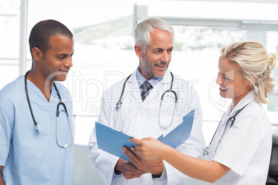 Three smiling doctors examining a file