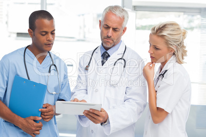 Three doctors using a tablet