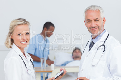 Smiling doctors standing in front of patient