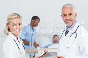 Smiling doctors standing in front of patient