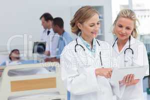 Two women doctors looking at tablet