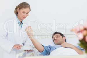 Woman doctor taking the blood pressure of male patient