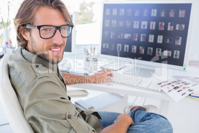 Photo editor turning and smiling at his desk
