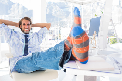 Designer relaxing at desk with no shoes and smiling