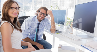 Designers sitting at their desk and smiling at camera