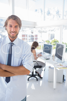 Smiling desginer standing in office with arms crossed