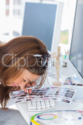 Editor using magnifying loupe to view the contact sheet