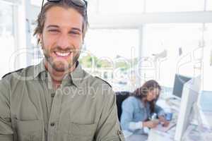 Cheerful man in creative office with arms folded