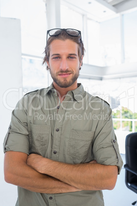 Smiling man in creative office with arms folded