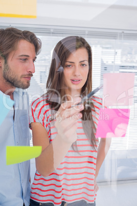 Woman showing sticky note to her colleague