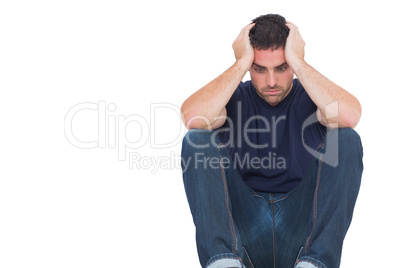 Sad man sitting on the floor while holding his head