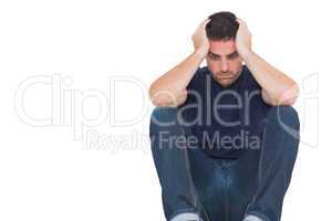 Sad man sitting on the floor while holding his head