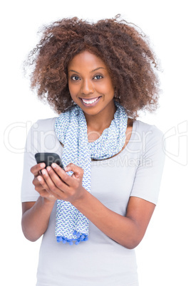 Smiling woman looking at camera and typing a text message Smiling woman looking at camera and typing a text message