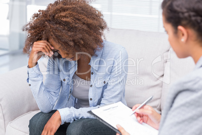 Woman sitting on sofa and crying in therapy