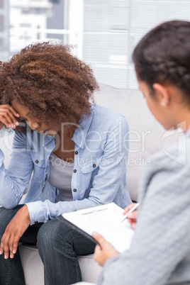 Upset woman crying on the sofa in therapy