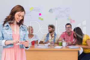 Woman using tablet with creative team working behind her
