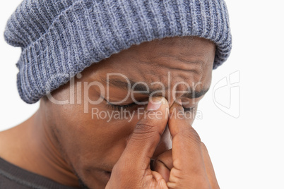 Man in beanie hat wincing with a headache