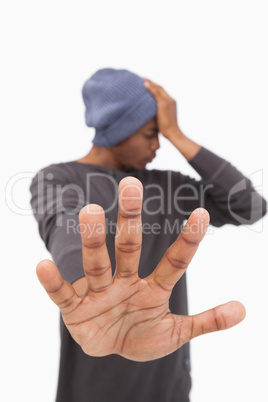 Man in beanie hat holding hand out to stop