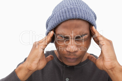 Man in beanie hat wincing with pain of headache