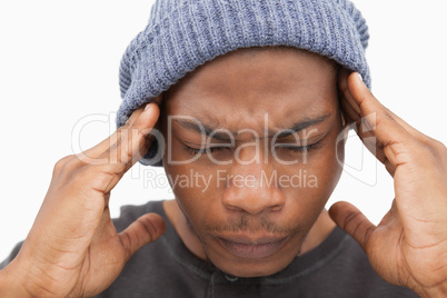 Man in beanie hat grimacing with pain of headache