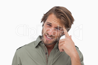 Man with headache touching his head and looking at camera