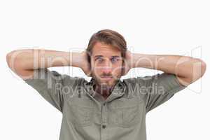 Man blocking his ears and looking at camera