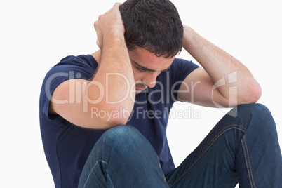 Unhappy man with head in hands sitting on floor