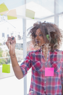 Woman with check shirt drawing on flowchart with marker